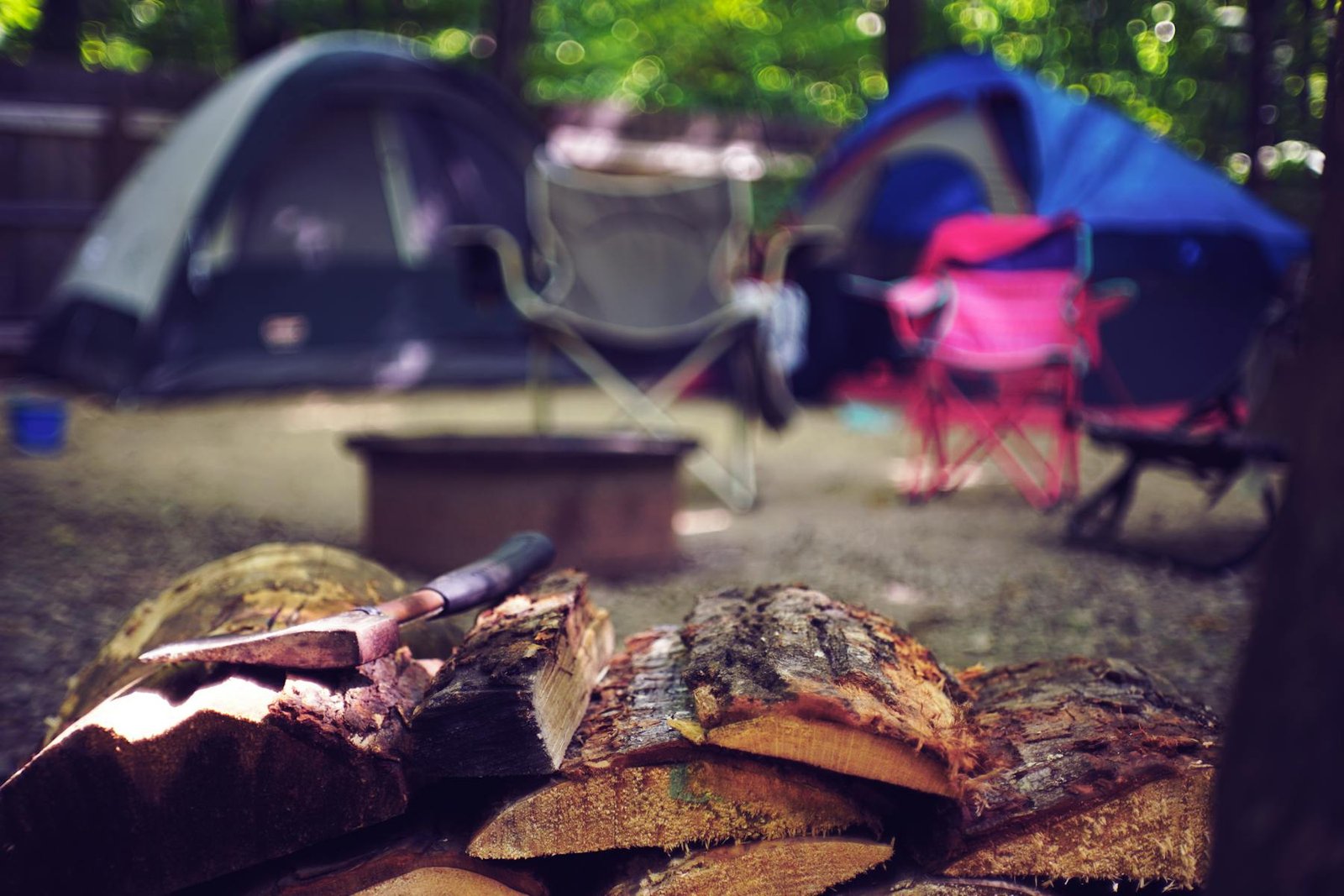 Campsite with tent chairs and stacked firewood