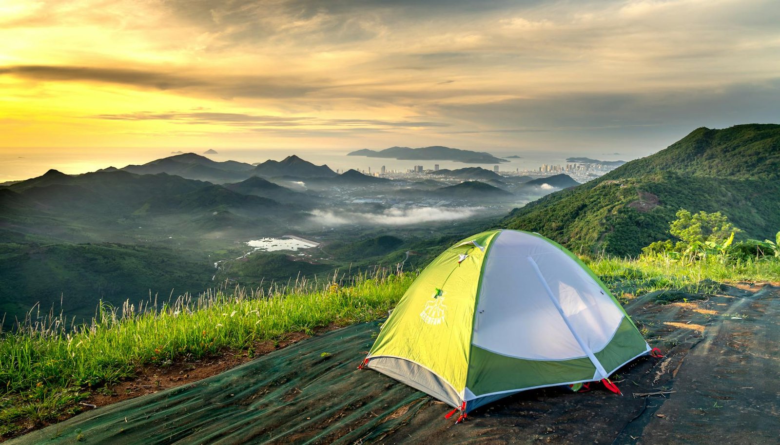 Tent pitched near a mountain cliff at sunset
